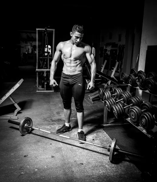 Hombre joven haciendo ejercicio en el gimnasio oscuro y viejo — Foto de Stock