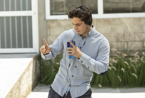 handsome and elegant man listen to music with headphones and dance in outdoors
