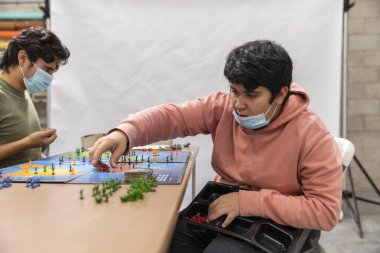 COVID-19 hastalık karantinası sırasında yüz maskesi takmış bir grup genç oyun oynuyor..