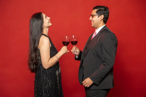 Couple in love toasting with wine glasses on red background. Valentine\'s Day.