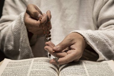 Kutsal İncil ve kutsal tespih ile karanlık bir gecede Tanrı 'ya dua eden İsa Mesih.