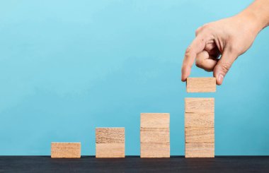 Ahşap blok mavi arka planda basamak merdiveni olarak istifleme, iş büyüme konseptinde başarı merdiveni.