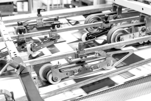 Close up of an offset printing machine during production. Black and white.