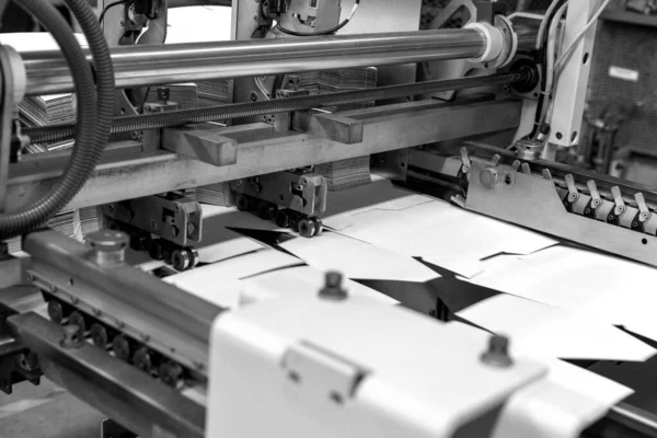 Close up of an offset printing machine during production. Black and white.