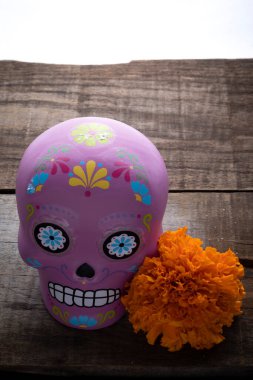 Tipik Meksika kafatası ve kırsal ahşap masa üzerindeki cempazuchitl çiçekleriyle kompozisyon.