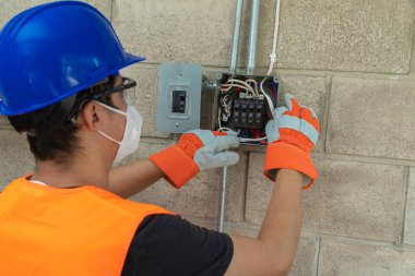 Genç elektrikçi COVID-19 salgını sırasında bir evin elektrik sistemini tamir ediyor ve sosyal ağlar için video dersi veriyor.