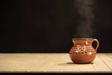 Lezzetli kahve fincanından çıkan buhar ya da ahşap masa üzerindeki sıcak çikolata ve siyah arka plan.