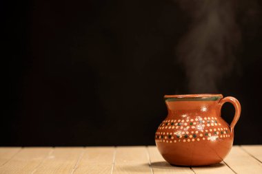 Kahve fıskiyesi ahşap masada kil sürahide servis ediliyor..