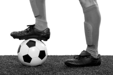 Futbolcu ayağının beyaz arka planda çimlerin üzerinde bir topa bastığının ayrıntıları. Siyah ve beyaz.