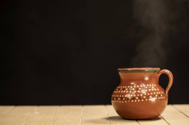 Lezzetli kahve fincanından çıkan buhar ya da ahşap masa üzerindeki sıcak çikolata ve siyah arka plan.