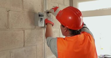 Erkek elektrikçinin portresi bir fabrikada elektrik tesisatı yaparken performans sergiliyor..