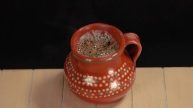 Kahve fıskiyesi ahşap masada kil sürahide servis ediliyor..