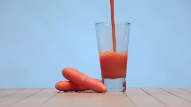 Καρότο Juiceinto Διαφανές Γυάλινο Κύπελλο Στο Ξύλινο Τραπέζι Μπλε Φόντο — Αρχείο Βίντεο