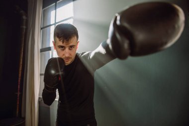 Adam spor salonunda boks yapan bir sporcu. Boksör ringde yumruk pratiği yapıyor. Gölge boksu. Sporcu kum torbasıyla saldırır. 4k video