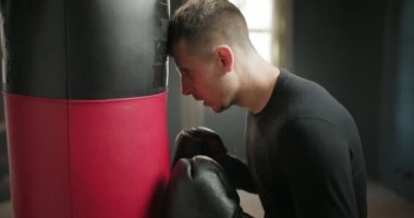 Eğitimden sonra yorgun boksör. Bir boksör kum torbasının yanında durur. 4k ağır çekim videosu