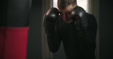 Bir boksör kum torbasını yener. Boksör ringde yumruk pratiği yapıyor. Sporcu kum torbasıyla saldırır. 4k video
