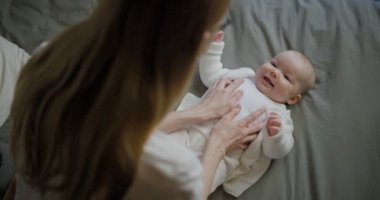 Güzel, gülümseyen bebek: Yatağa uzanmış güzel, küçük bir bebek kameraya gülümsüyor..