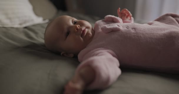 Belle Bébé Souriant : Un magnifique petit bébé se trouve sur le lit et sourit à la caméra avec un joli fond de mise au point douce. — Video