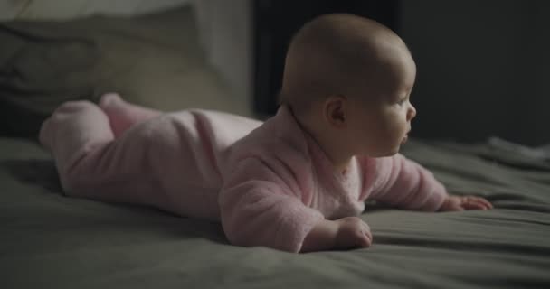 美しい赤ちゃんは彼の胃の上にあり、カメラを見て、美しい女の子は赤ちゃんです. — ストック動画