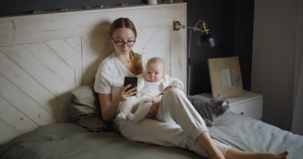 Fiatal nő babával szelfit készít. Egy kismamának van egy videohívása. Modern fiatal anya. Modern nő egy gyerekkel. — Stock videók