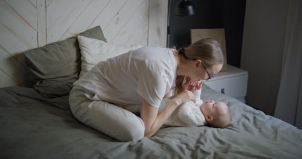 Η ευτυχισμένη γυναίκα κοιτάζει το μωρό της και χαμογελάει. Το όμορφο μωρό χαμογελάει στη μητέρα. Μητέρα με το δικό της μωρό.. — Αρχείο Βίντεο