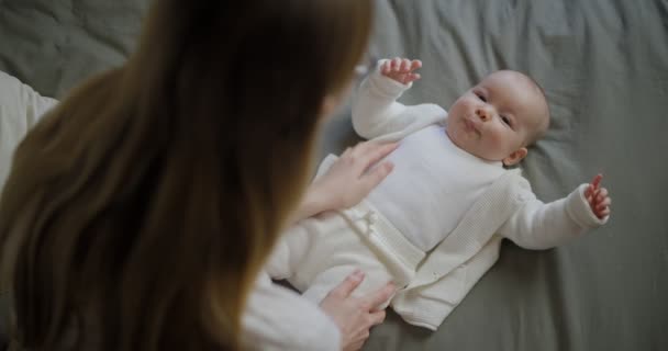 Glad kvinna tittar på sitt barn och ler. Vackra barn ler mot mamma. Mor med sitt eget barn. — Stockvideo