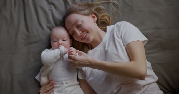 Счастливая женщина смотрит на своего ребенка и улыбается. Красивая малышка улыбается маме. Мать с собственным ребенком. — стоковое видео