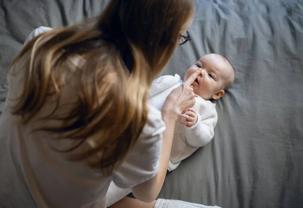 Happy woman looks at her baby and smiles. Beautiful baby smiles at mother. Mother with her own baby. Stock Photo