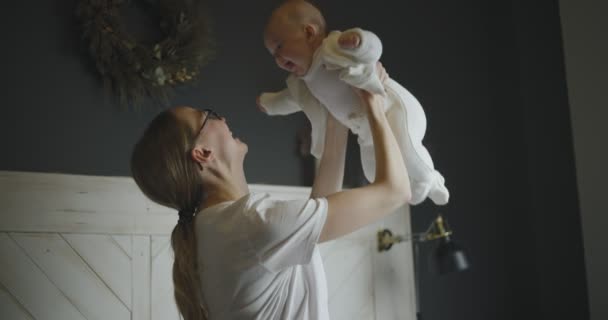 Счастливая девушка поднимает своего ребенка. Молодая мать с ребенком. Девочка смеется на руках матери. — стоковое видео
