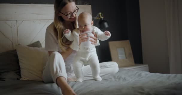 Hermosa madre con su bebé. Joven mujer hermosa mira a su hija pequeña. Niña riendo en sus brazos de madres. — Vídeos de Stock