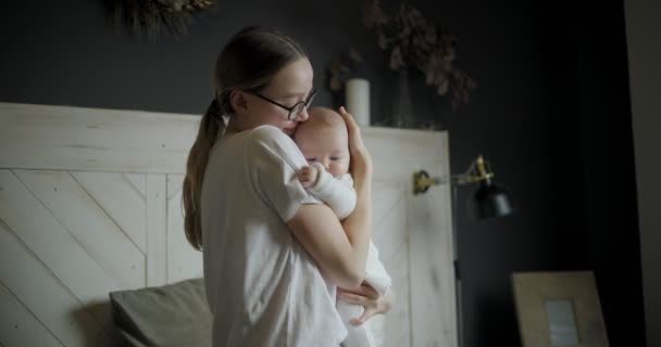 Beautiful mother with her baby. Young beautiful woman looks at her little daughter. Baby girl laughing in her mothers arms. — Stock Video