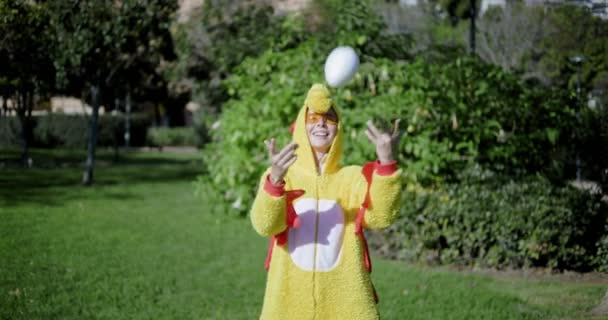 A girl dressed as a chicken throws an egg on top and catches it back. Funny video of a woman in a chicken costume. Chicken with egg. The girl and the chicken egg. — Stock Video
