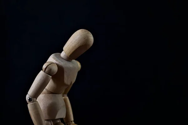 A portrait of a wooden mannequin showing emotion like sadness, loneliness, fear and depression on black background.
