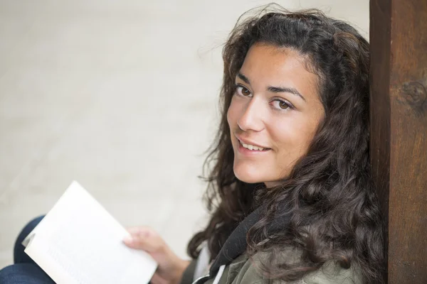 Sonrisa dentada de una joven leyendo en la calle . Imagen De Stock