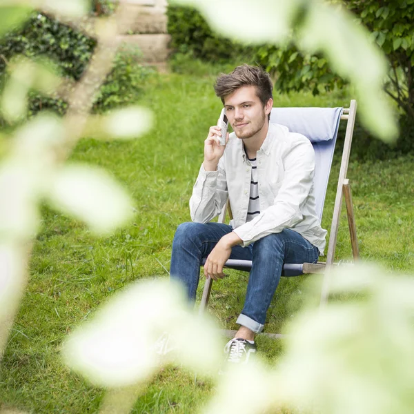 Focus on a cute young man waiting on telephone outdoors
