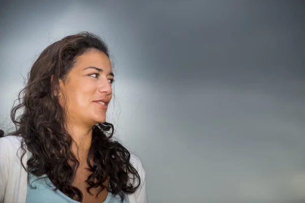 Jonge vrouw op profiel glimlachend en op zoek donkere cloudscape backg — Stockfoto