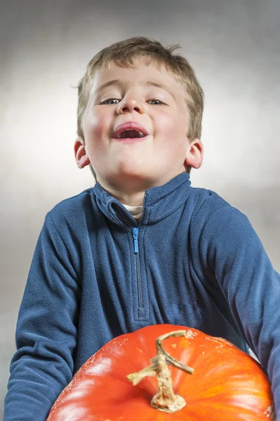 Little boy holding with difficulty a big pumpkin. Halloween them — Stock Photo, Image