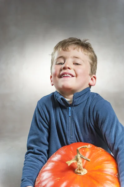 Little boy holding with difficulty an heavy pumpkin. Halloween t — Stock Photo, Image