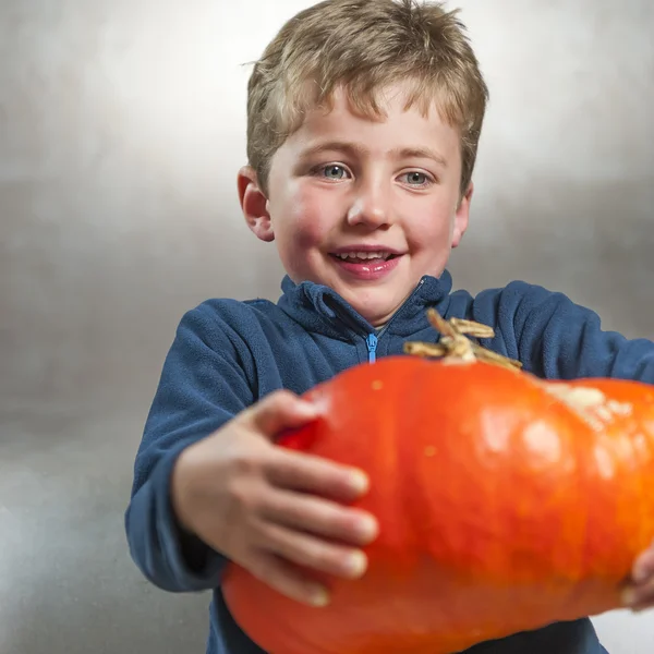 Little boy holding a big orange pumpkin. Halloween theme — Stock Photo, Image