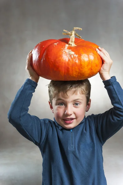 Portrait of little boy holding a pumpkin on his head — Stock Photo, Image