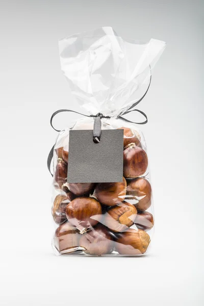 Contemporary gift with ribbon of chestnuts with black blank labe — Stock fotografie