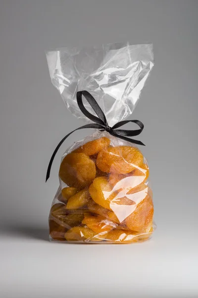 Luxury transparent bag of dried apricots isolated with elegant black ribbon — Stock Photo, Image