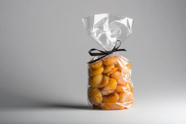 Luxury transparent bag of dried apricots with ribbon and copy space — Stock Photo, Image