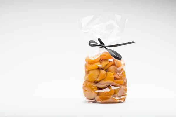 Ciseaux symboliques en ruban découpent un sac transparent d'abricots — Photo