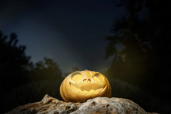 Abóbora de Halloween em uma rocha na escuridão — Fotografia de Stock