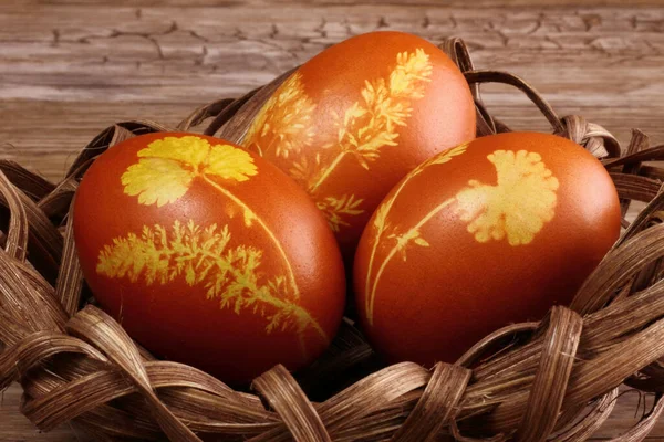 Easter natural colored eggs in basket - nest, wooden backgrund  - easter decoration