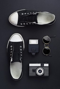 Spor ayakkabı, fotoğraf makinesi ve yuvarlak güneş gözlüğü