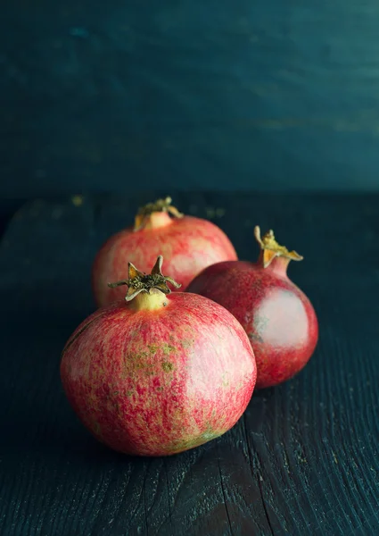 Pomegranates over dark wooden — Stock Photo, Image
