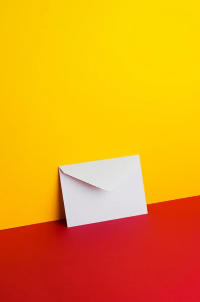 Envelope inclinado sobre amarelo e vermelho — Fotografia de Stock