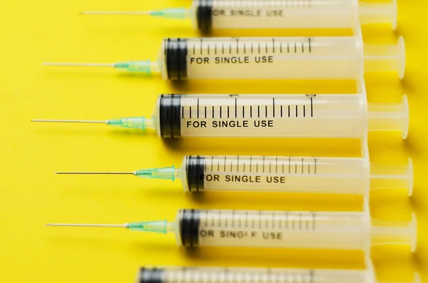 Detalhes de seringas sobre amarelo brilhante — Fotografia de Stock